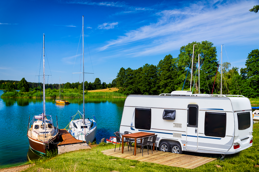 Caravan and sailboats by a lakeside.
